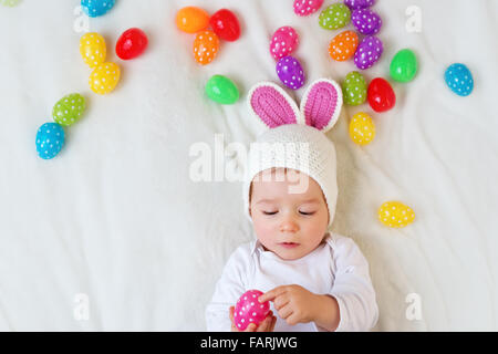 Baby Boy in Hase Hut auf grüne Decke liegend mit Ostereiern Stockfoto