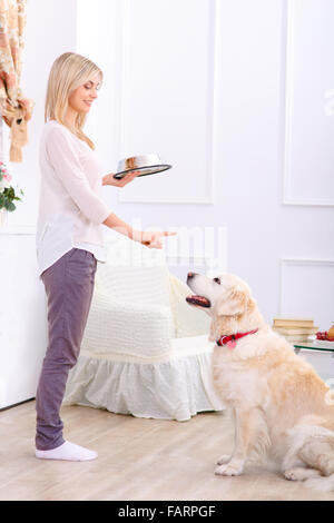 Fürsorgliche Frau, die Fütterung des Hundes Stockfoto