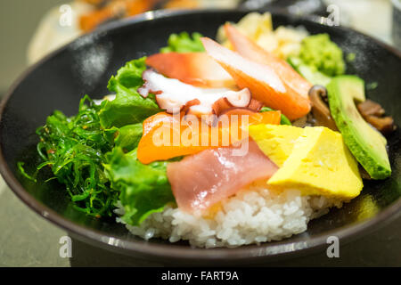 Eine Schüssel mit Chirashi (Chirashizushi), bestehend aus Sushi-Reis, garniert mit einer Vielzahl von rohem Fisch und Gemüse. Stockfoto