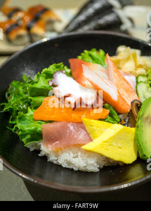 Eine Schüssel mit Chirashi (Chirashizushi), bestehend aus Sushi-Reis, garniert mit einer Vielzahl von rohem Fisch und Gemüse. Stockfoto