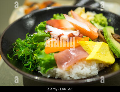 Eine Schüssel mit Chirashi (Chirashizushi), bestehend aus Sushi-Reis, garniert mit einer Vielzahl von rohem Fisch und Gemüse. Stockfoto