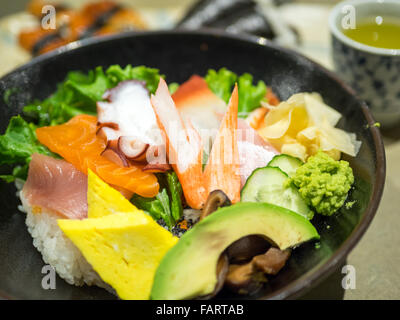 Eine Schüssel mit Chirashi (Chirashizushi), bestehend aus Sushi-Reis, garniert mit einer Vielzahl von rohem Fisch und Gemüse. Stockfoto