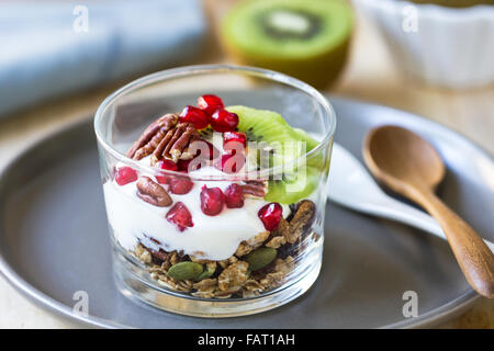 Müsli mit Joghurt, Kiwi und Granatapfel in einem Glas Stockfoto