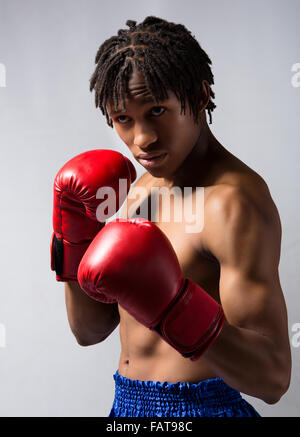 Junge muskulöse athletische männliche Boxer blaue Boxershorts und rote Boxhandschuhe. Stockfoto