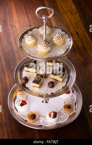 Eine Auswahl an leckeren Desserts angeordnet und auf eine silberne Etagere im Stil eines englischen High Tea serviert. Stockfoto