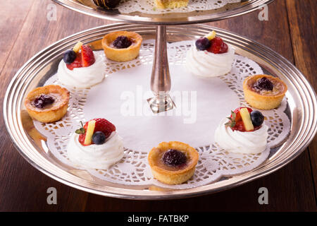 Eine Auswahl an leckeren Desserts angeordnet und auf eine silberne Etagere im Stil eines englischen High Tea serviert. Stockfoto