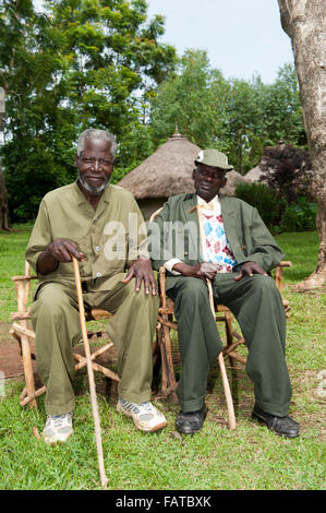 Paar der Dorfältesten sitzen auf hausgemachten Stühlen am Dorfplatz, Kenia. Stockfoto