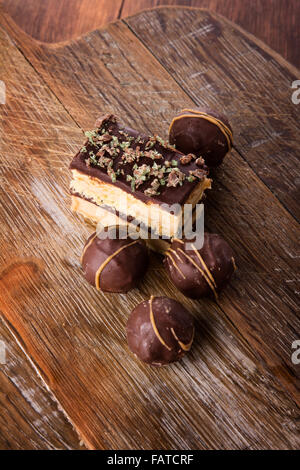 Eine Auswahl an köstlichen Pralinen und Kuchen serviert auf einem Holzbrett. Stockfoto