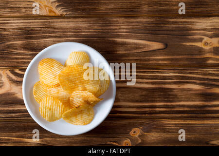 Kartoffel-Chips auf dem hölzernen Hintergrund. Stockfoto