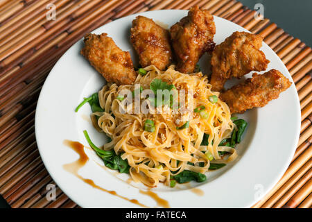 Chicken Wings mit Nudeln und Spinat Stockfoto