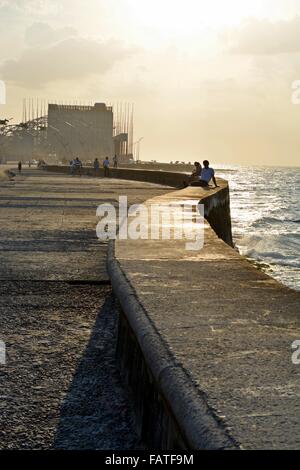 lokale Leute anfangen zu sammeln in der Abendsonne zum bummeln oder sitzen auf dem Deich entlang des Malecon in Havanna Stockfoto