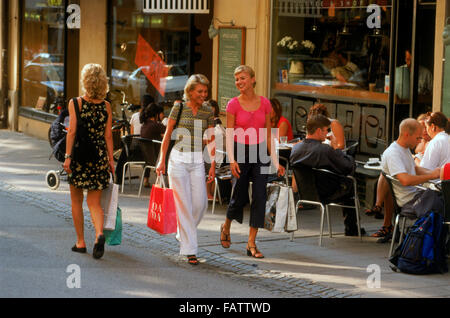 Drei Schwedinnen mit Einkaufstüten vorbeigehen Bürgersteig Restaurant in Stockholm Straße im Sommer Stockfoto