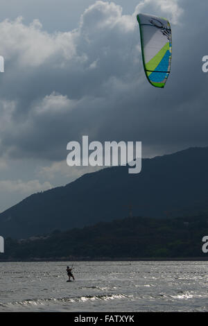 Weibliche Kitesurfer mit Drachen in der Bucht Stockfoto