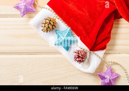 Weihnachtsmütze mit Weihnachtsschmuck auf Holztisch Stockfoto