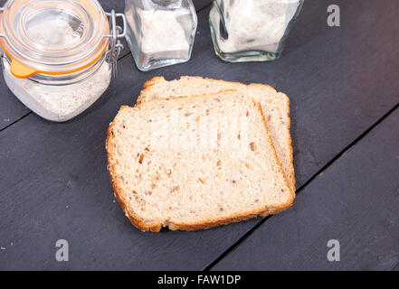 Glutenfreies Brot mit Blume auf schwarzem Hintergrund aus Holz Stockfoto