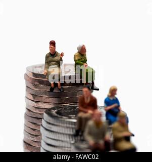 6 Miniatur-Leute sitzen auf Stapel von britischen Geld Münzen Stockfoto