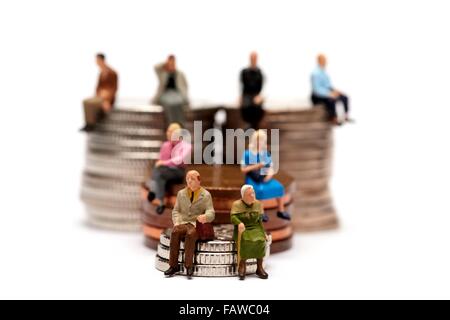 8 Miniatur-Leute sitzen auf Stapel von britischen Geld Münzen Stockfoto