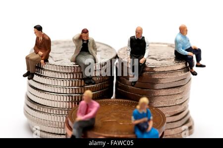 6 Miniatur Leute sitzen auf einem Haufen von britischen Geld Münzen Stockfoto