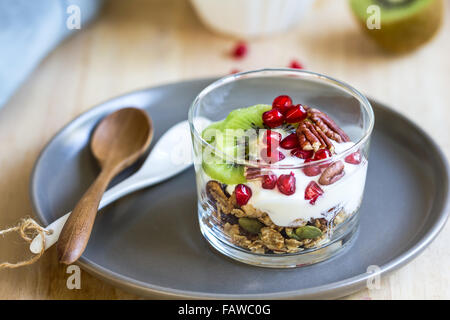 Müsli mit Joghurt, Kiwi und Granatapfel in einem Glas Stockfoto