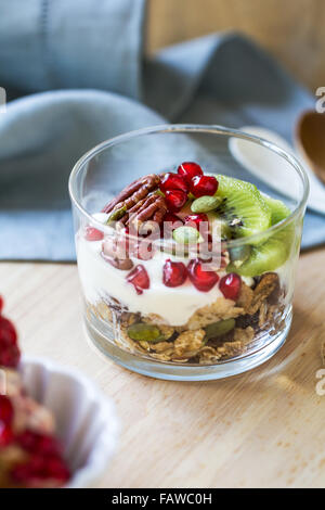 Müsli mit Joghurt, Kiwi und Granatapfel in einem Glas Stockfoto