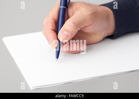 Menschliche Hand mit einem Stift schreiben auf eine weiße ohne Gegentor. Stockfoto