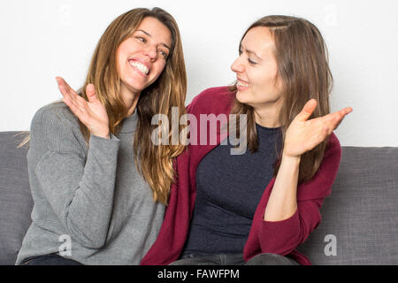 Zwei Freundinnen Spaß beim Sitzen auf Trainer im Wohnzimmer Stockfoto