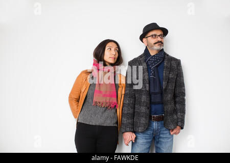 Persischer Mann und tibetische Frau Hand in Hand und eine Wand gelehnt, wegsehen, während Frau Mann sucht Mann; Toronto, Ontario, Kanada Stockfoto