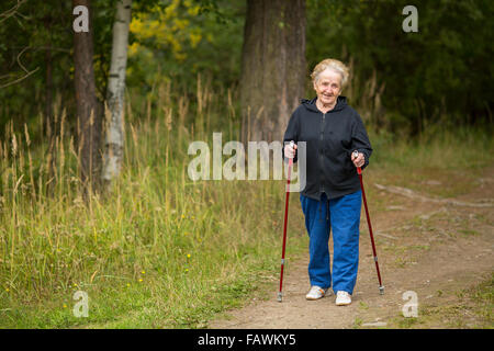 Eine ältere Frau üben Nordic-walking-außerhalb der Stadt. Stockfoto