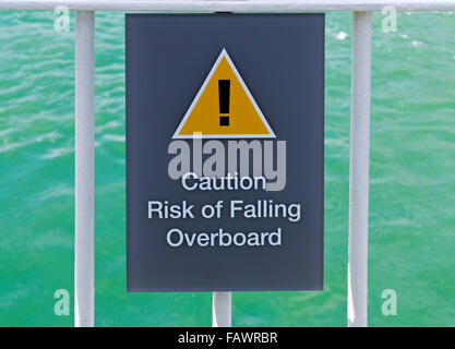 Vorsicht Gefahr von fallen über Bord Warnschild mit gelben Gefahr Dreieck und Ausrufezeichen auf einem Passagierschiff auf dem Meer Stockfoto