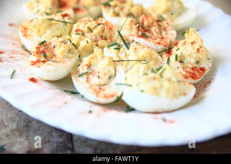 Deviled Eiern mit geräucherter Paprika und Schnittlauch auf einer weißen geriffelten Platte Stockfoto