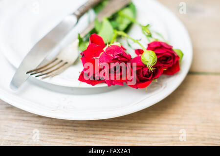 Tischdekoration für den St. Valentinstag mit Gläsern Wein, Geschenkbox und rote Rosen im rustikalen Stil Stockfoto