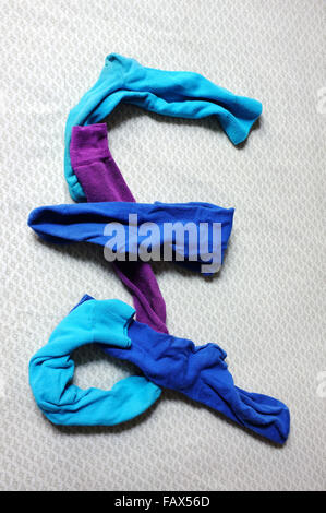 Das Pfund-Symbol aus bunten Socken einen Bettbezug Handauflegen gemacht. Stockfoto