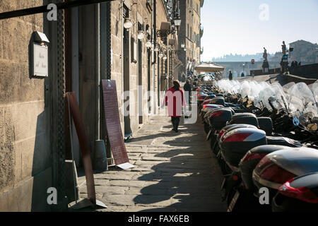 Frau im roten Mantel zu Fuß entlang Lungarno Corsini in Florenz, Italien Stockfoto