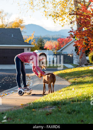 REDDING, CA, USA - 24. November 2015: Teenager-Mädchen Spaziergänge mit Hund selbstbalancierende Zweirad-Roller, auch genannt ein Hoverboard. Stockfoto