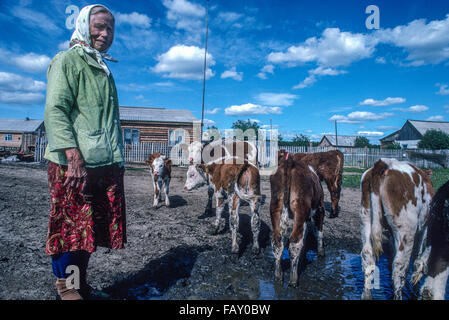 Eine Seniorin sibirische Frau arbeitet mit ihrem Vieh außerhalb ihrer Wohnung in der Region Krasnojarsk, Sibirien, Russland. Stockfoto