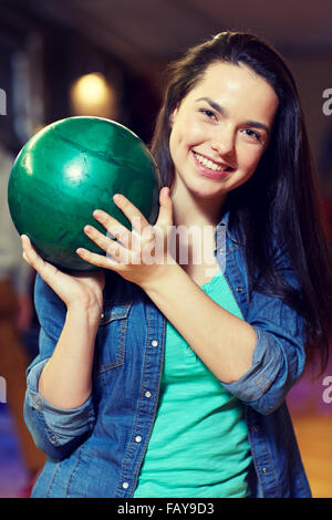 glückliche junge Frau mit Ball in Bowlingclub Stockfoto