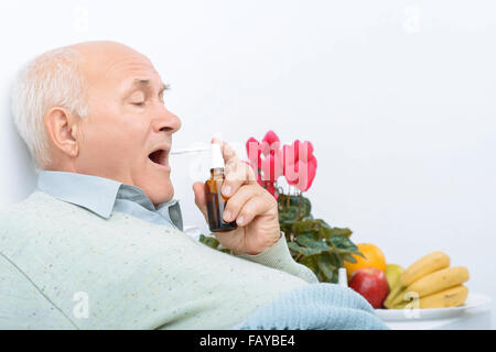 Müden senior Gentleman nutzt seine Halsschmerzen-Spray. Stockfoto