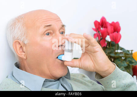 Senior gealterter Mann nutzt Inhalator um seinen Schmerz zu heilen. Stockfoto