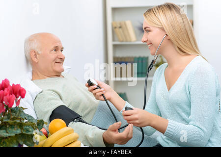 Jugendliche besuchen relative misst Blutdruck des Patienten. Stockfoto