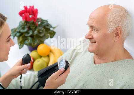 Junge Enkelin verwendet Stethoskop, um Blutdruck zu überprüfen. Stockfoto