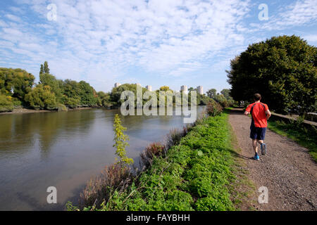 Ein Mann läuft entlang der Leinpfad in Richtung Kew Bridge über die Themse, London, England, UK Stockfoto