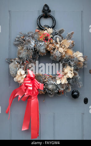 dekorativer Weihnachtskranz grauen Tür hängen Stockfoto