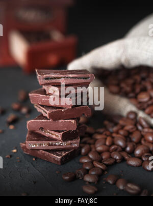 Frisch gerösteten Kaffeebohnen und Stapel von brauner Schokolade auf dunklen Tisch. Stockfoto