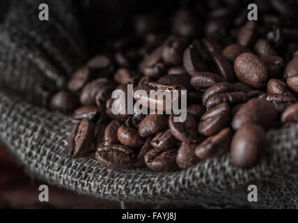 Beutel mit Kaffeebohnen auf einem dunklen Hintergrund. Makro. Geringe Schärfentiefe. Stockfoto