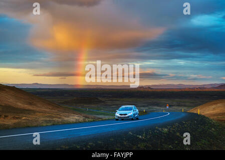 Land straße mit Regenwolken und Regenbogen in der Nähe des Sees Myvatn, Island. Stockfoto