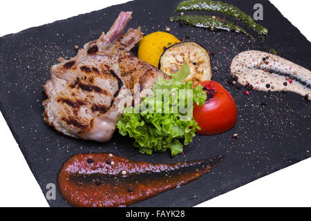 Gegrilltes Kalbfleisch hacken auf den Knochen mit Sauce und Gemüse Stockfoto