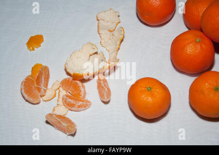 Menge an Reife Mandarinen, Scheiben und schälen auf weißen Tisch Stockfoto