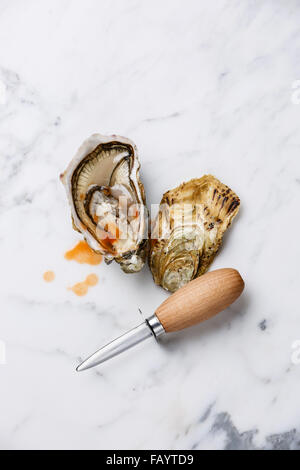 Oyster und Oyster Messer auf weißem Marmor Hintergrund mit pikanter sauce Stockfoto