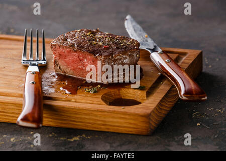 Filet Mignon Steak auf Holzbrett auf schwarzem Hintergrund Stockfoto
