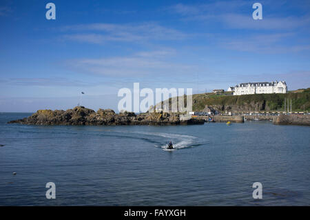 Ein Jet-Ski-Fahrer im Hafen von Portpatrick, Dumfries and Galloway, Schottland. Das Portpatrick Hotel auf der Klippe über. Stockfoto